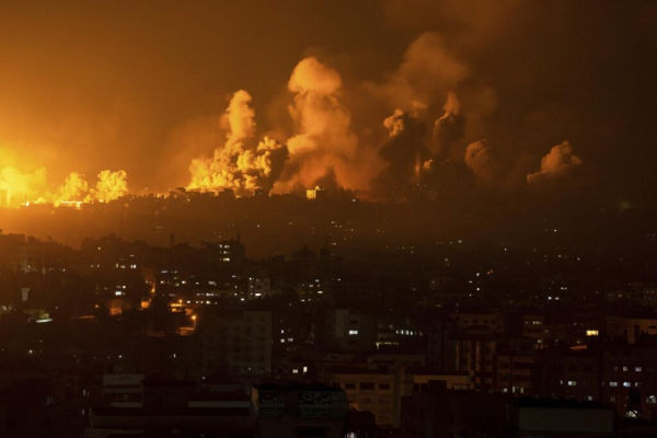 Bombenabwurf über einer Stadt bei Nacht. Der Himmel ist grell erleuchtet.